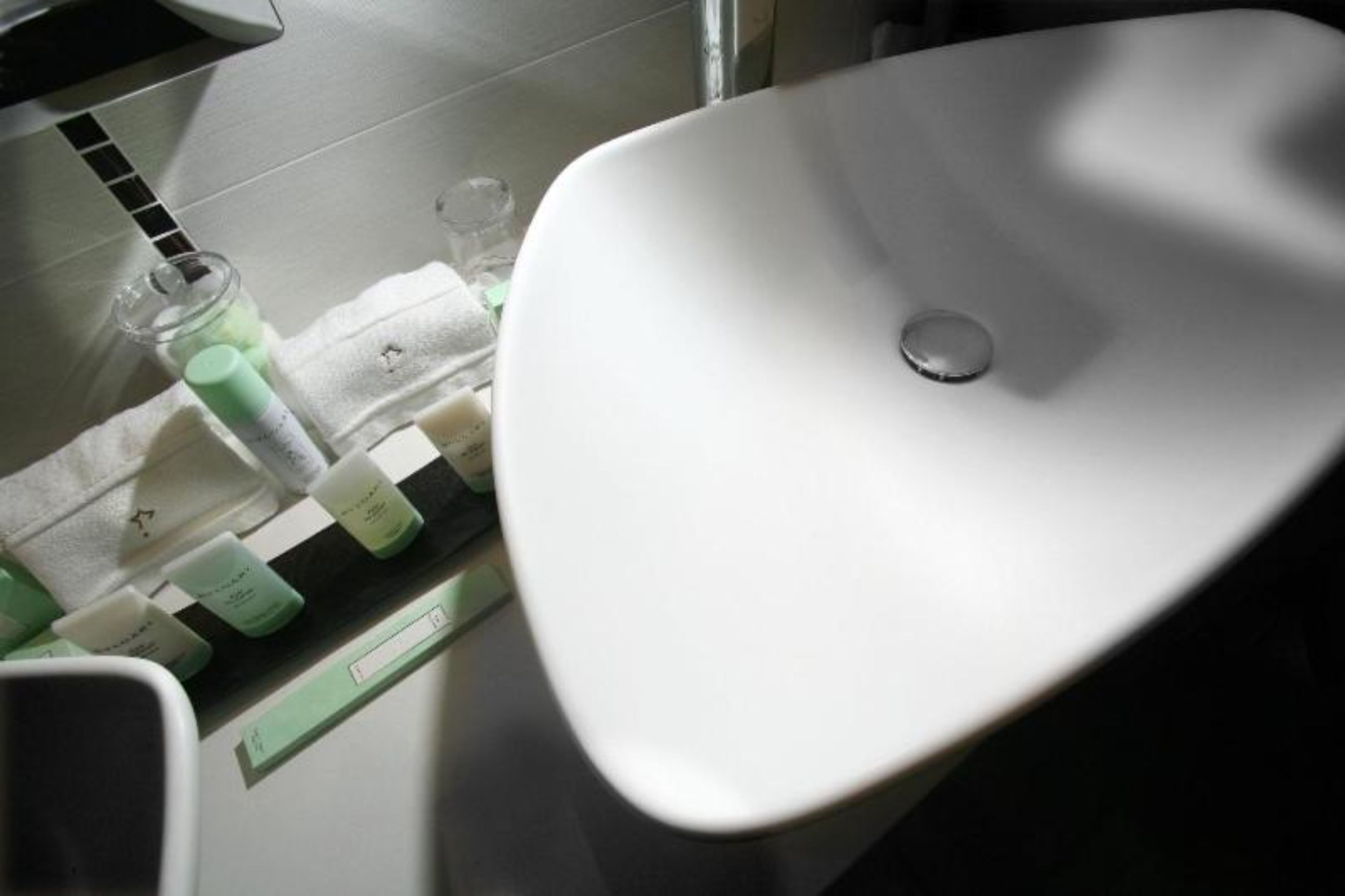 A bathroom with a white sink, a mirror, and toiletries on the counter.