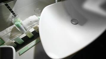 A bathroom with a white sink, a mirror, and toiletries on the counter.