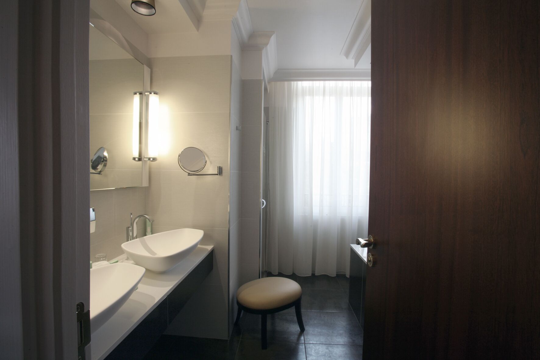 A modern bathroom with two sinks, a mirror, and a shower.