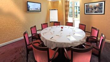 A conference room with a round table, red chairs, a projector screen, and a whiteboard.