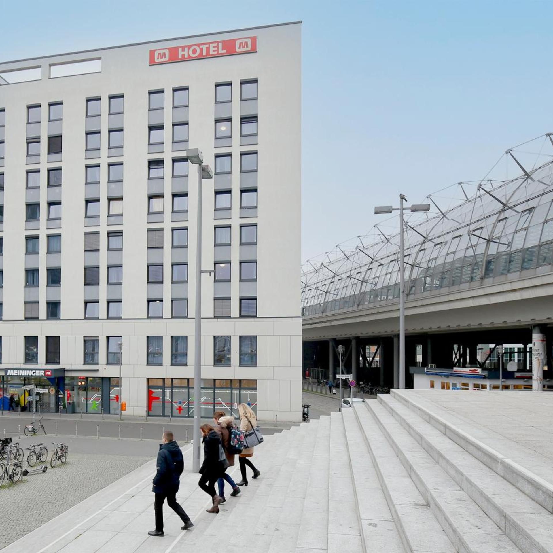 Un moderno edificio de hotel con un letrero llamativo, una marquesina y una zona de estacionamiento para bicicletas.