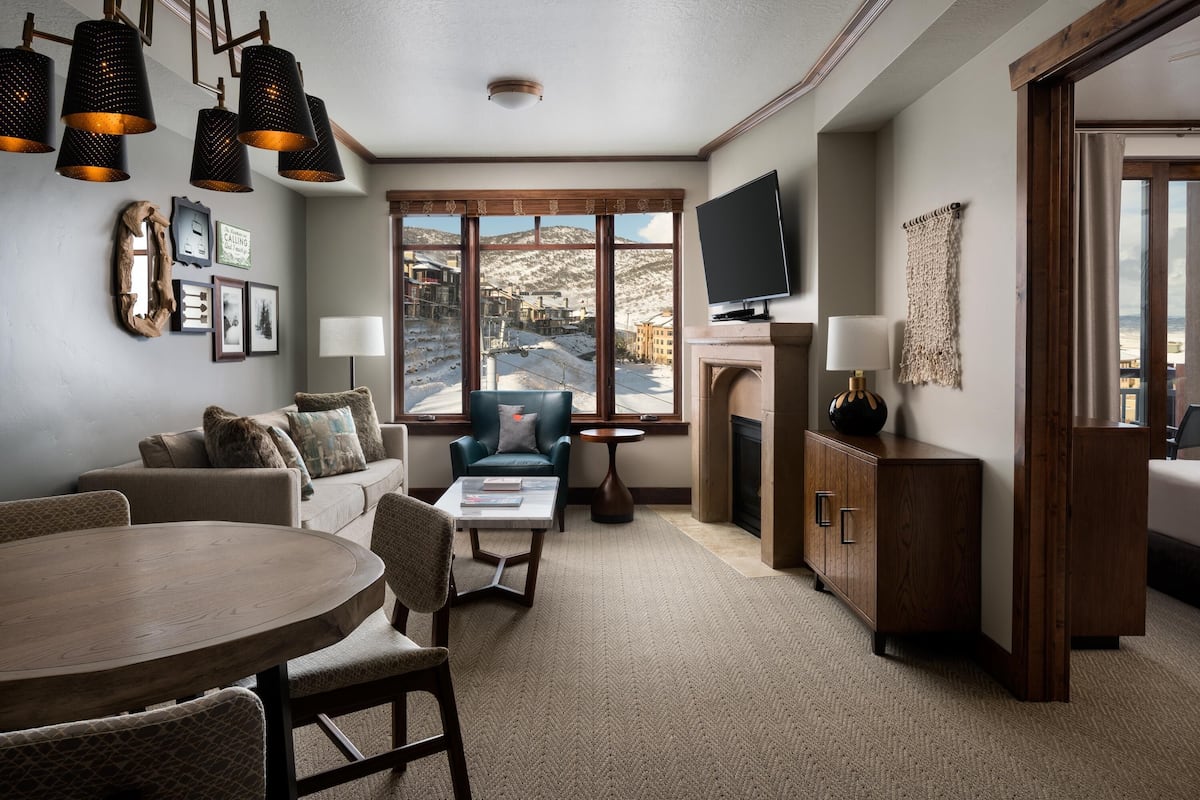 A modern living room with a fireplace, a television, and a large window offering a view of a snowy landscape.