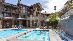 A pool area with a waterfall feature, lounge chairs, and a building with multiple balconies. - Hyatt Centric Park City (Park City)