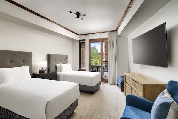 Habitación de hotel con dos camas, televisión de pantalla plana, escritorio y balcón con vistas.