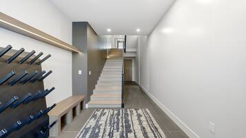 A modern staircase with a wooden handrail and a bench at the bottom.