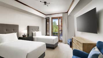 Habitación de hotel con dos camas, televisión de pantalla plana, escritorio y balcón con vistas.