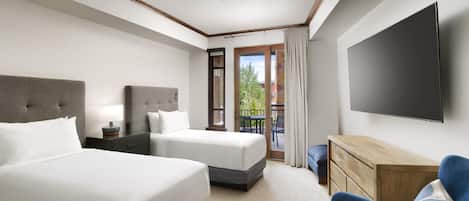 Habitación de hotel con dos camas, televisión de pantalla plana, escritorio y balcón con vistas.