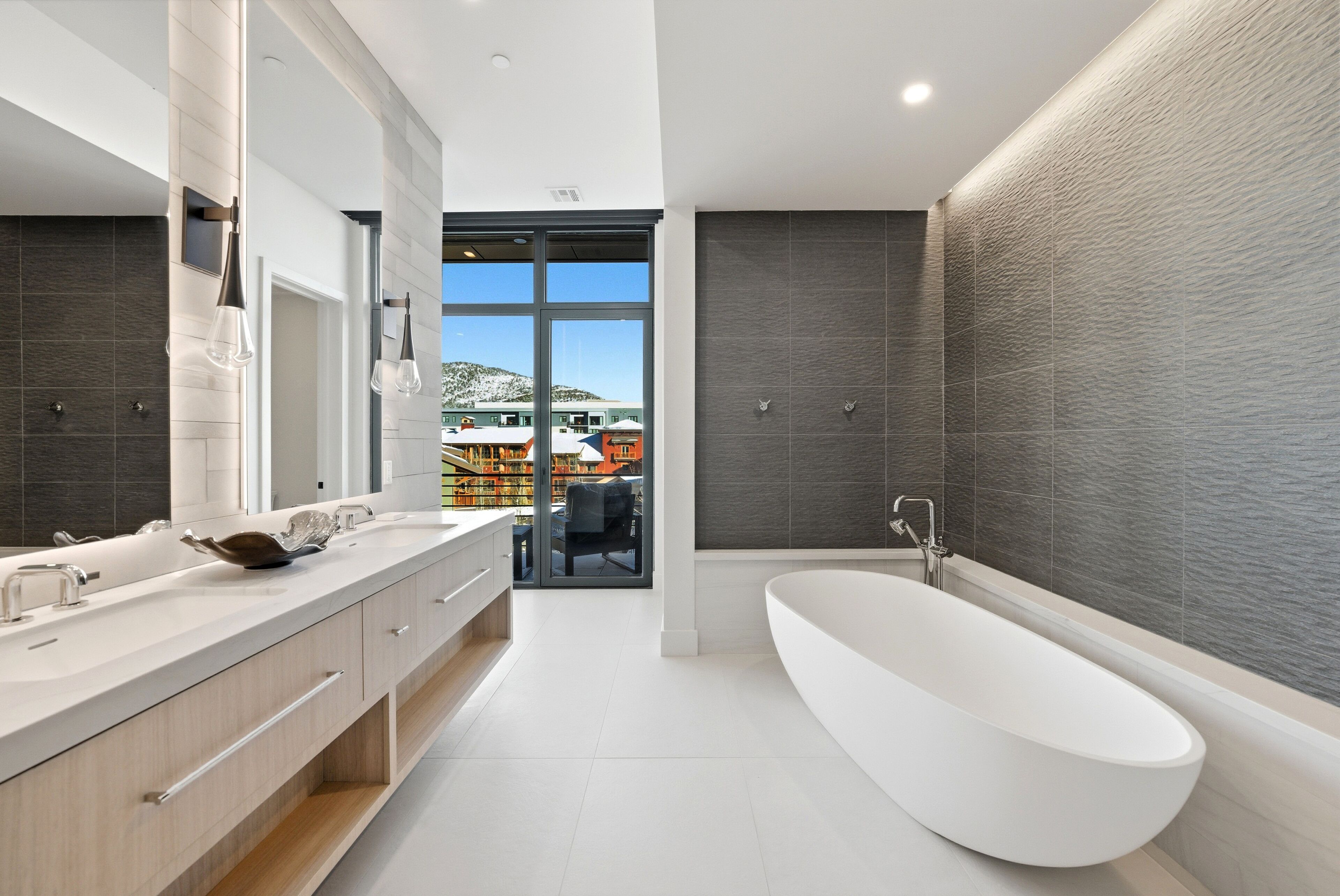 A modern bathroom with a freestanding bathtub, a large mirror, and a vanity with a double sink.