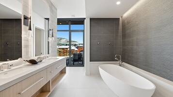 A modern bathroom with a freestanding bathtub, a large mirror, and a vanity with a double sink.