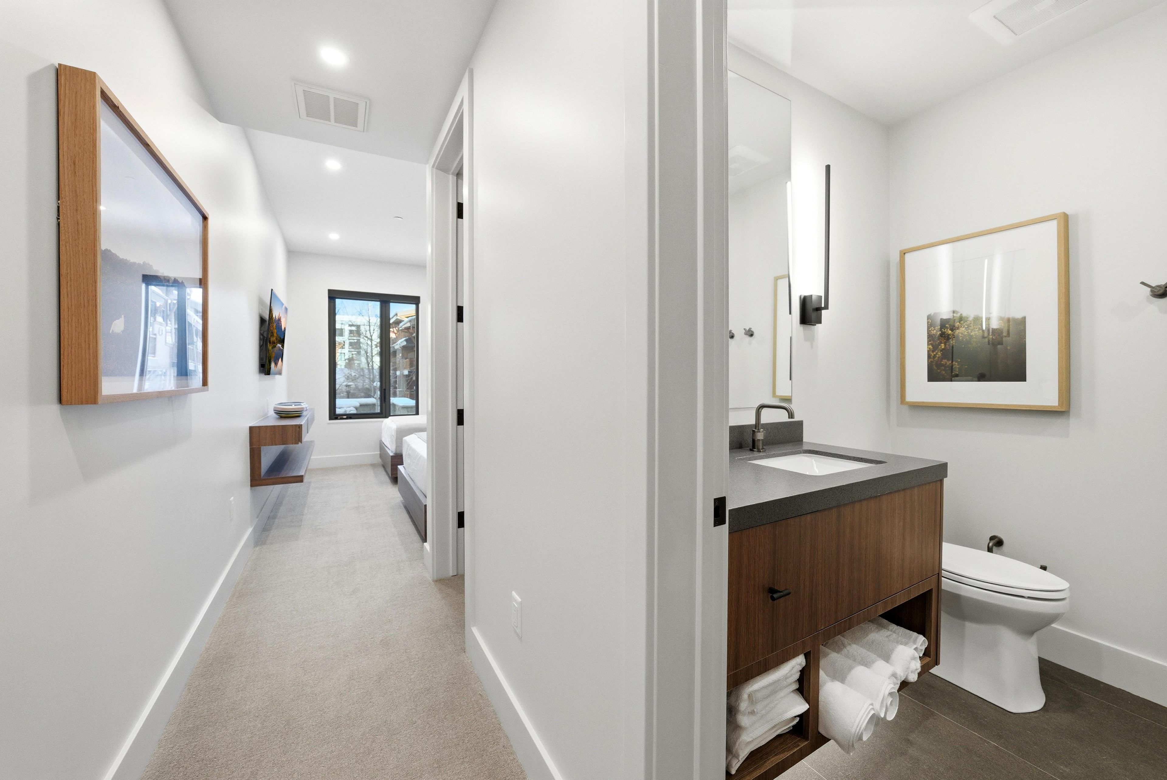 Une salle de bain moderne avec un grand miroir, des toilettes et un lavabo.