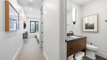 A modern bathroom with a large mirror, a toilet, and a sink.