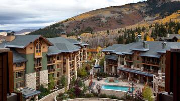 A resort with multiple buildings, a swimming pool, and a mountainous backdrop.