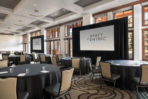 A conference room with multiple round tables, chairs, and a large screen displaying "HYATT CENTRIC PARK CITY". - Hyatt Centric Park City (Park City)