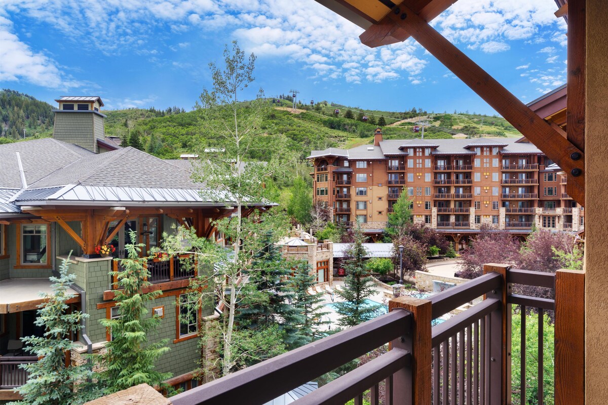 Un hotel con varias plantas, una zona de piscina y vistas a un paisaje montañoso.