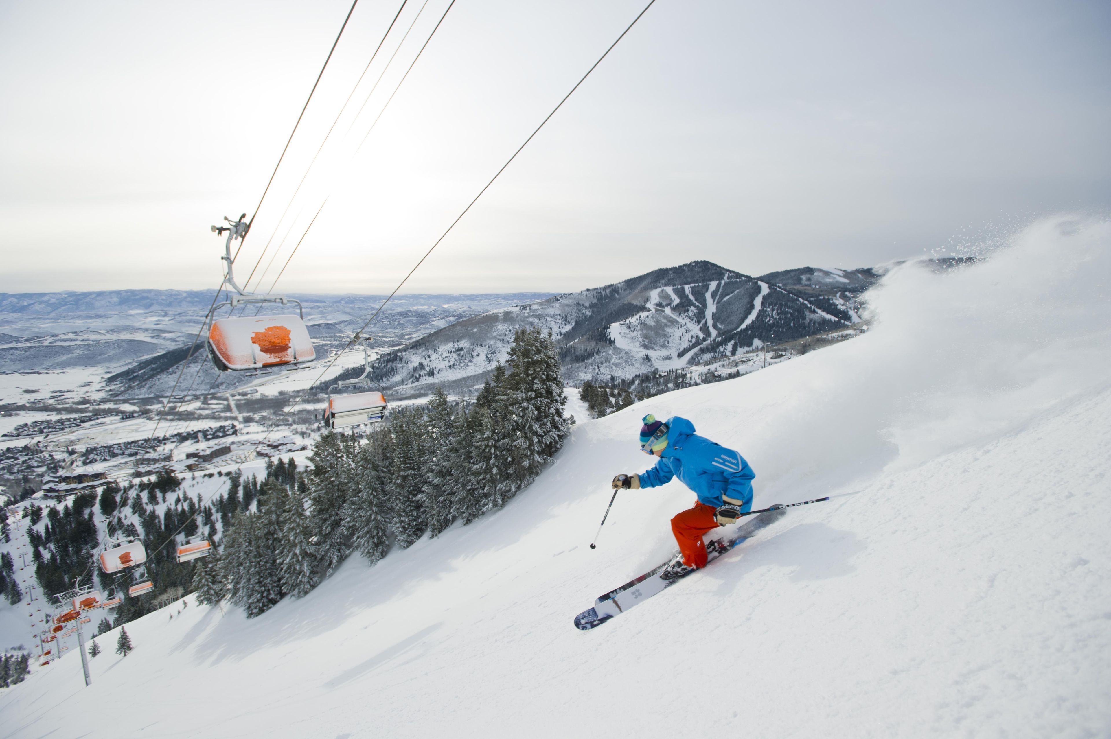 A ski slope with a ski lift and a skier in motion.