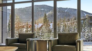 A room with large windows offering a view of snow-covered mountains and trees.