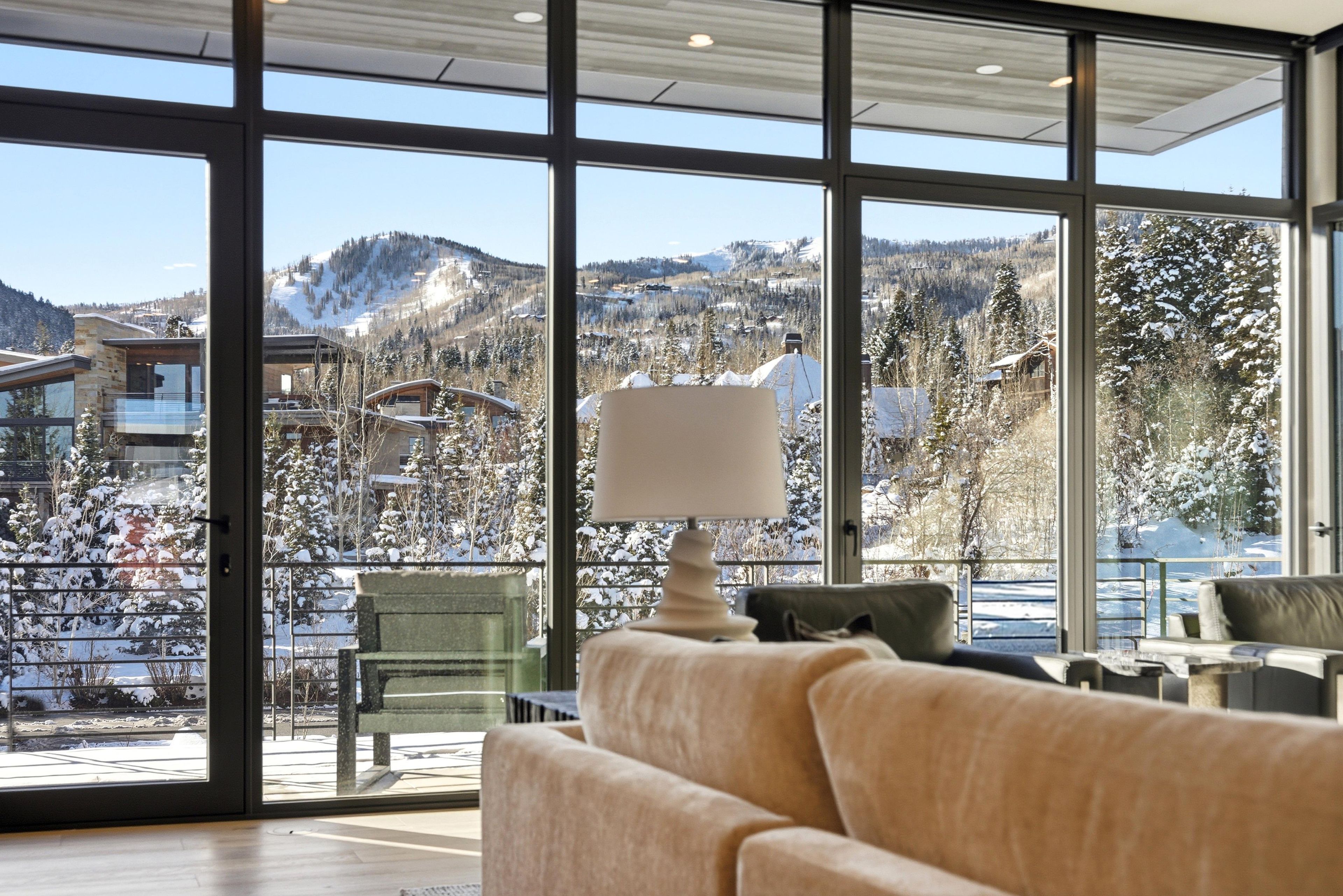 Un intérieur moderne avec de grandes fenêtres donnant sur un paysage montagneux enneigé.