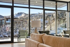 Ein modernes Interieur mit großen Fenstern und Blick auf eine verschneite Berglandschaft.