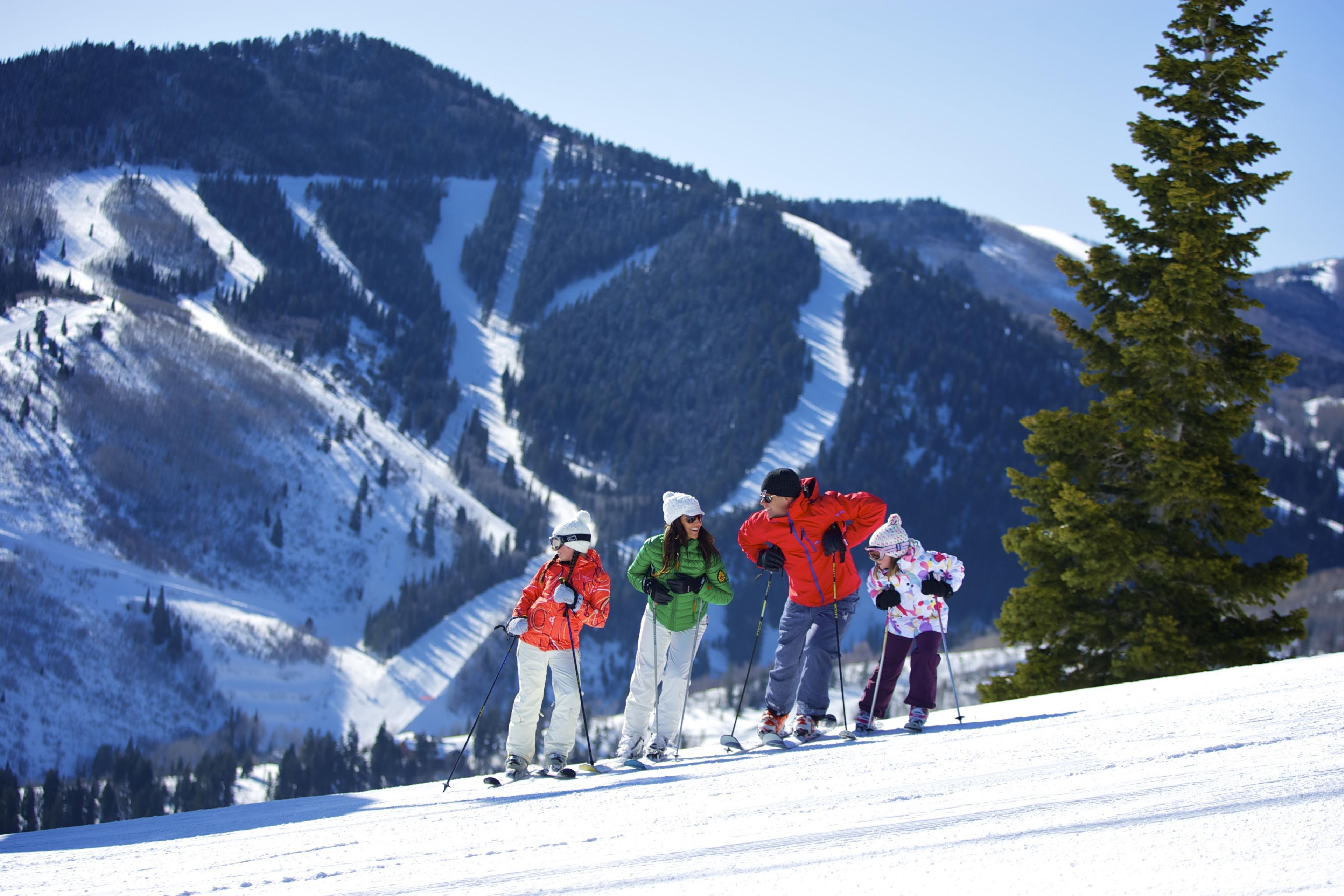 A group of skiers on a snowy slope with a mountain backdrop.