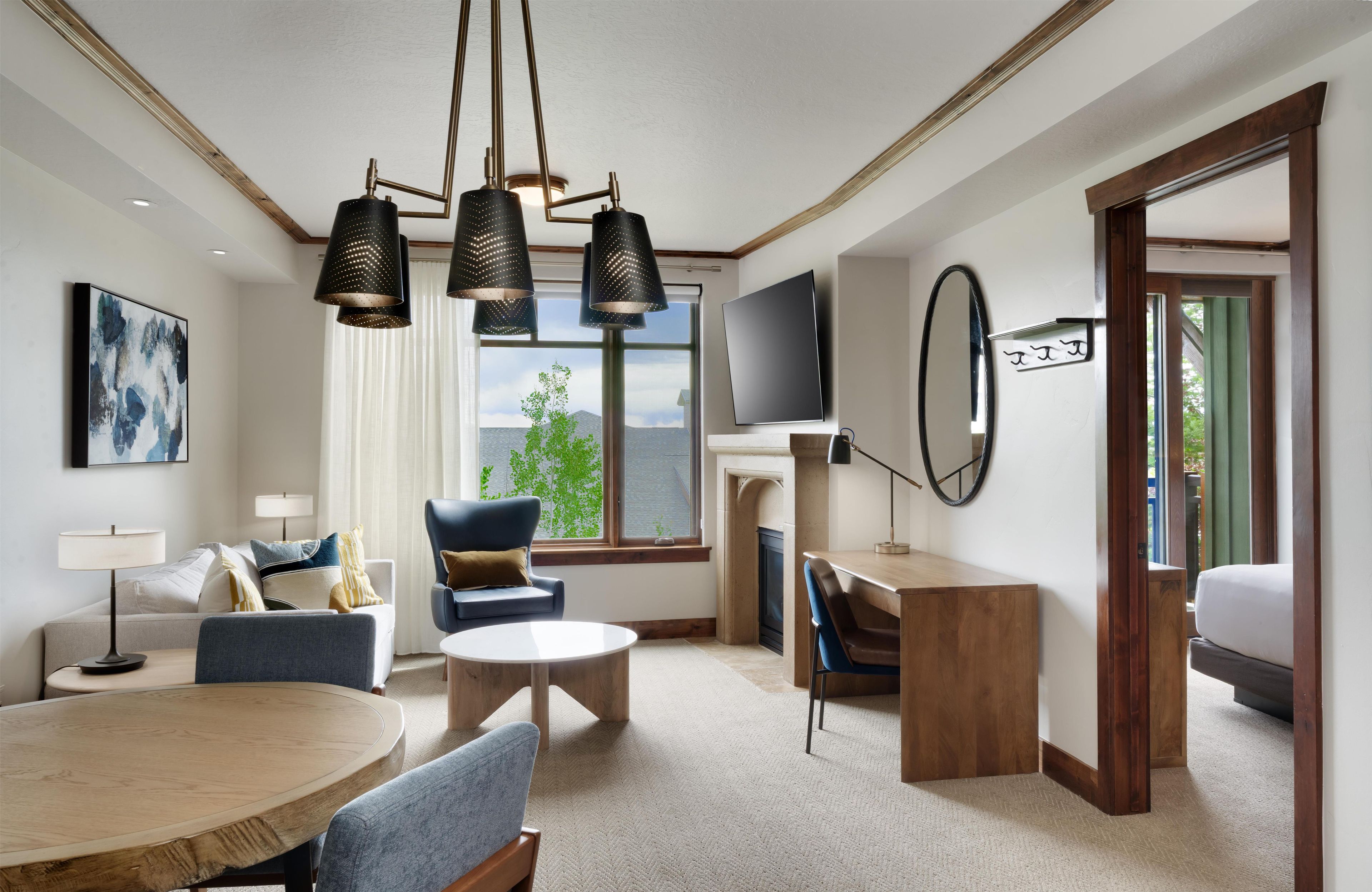 Habitación de hotel con comedor, sofá, televisión y chimenea.