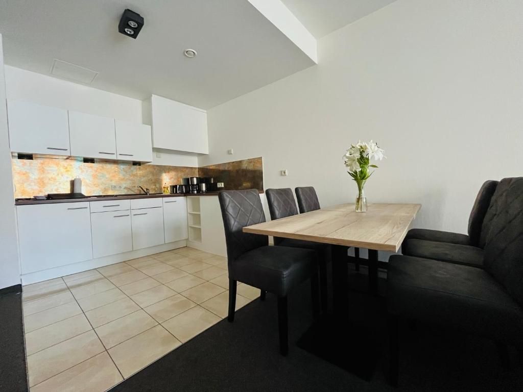 A modern kitchen with white cabinets, a wooden countertop, and a dining area with a table and chairs.