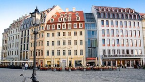 A cobblestone square with historic buildings, outdoor seating, and a bicycle. - Aparthotel Altes Dresden (Dresden)