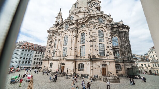 A historic building with a large central dome and multiple smaller domes, surrounded by a cobblestone square with pedestrians and bicycles. - Aparthotel Altes Dresden (Dresden)