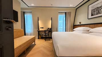 Habitación de hotel con cama, escritorio, silla, sofá y un cuadro en la pared.