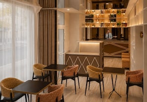 Un hall d’hôtel comprenant un bar, des espaces aménagés avec des sièges et une vue à travers les rideaux.