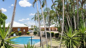 A swimming pool surrounded by palm trees and a brick building.