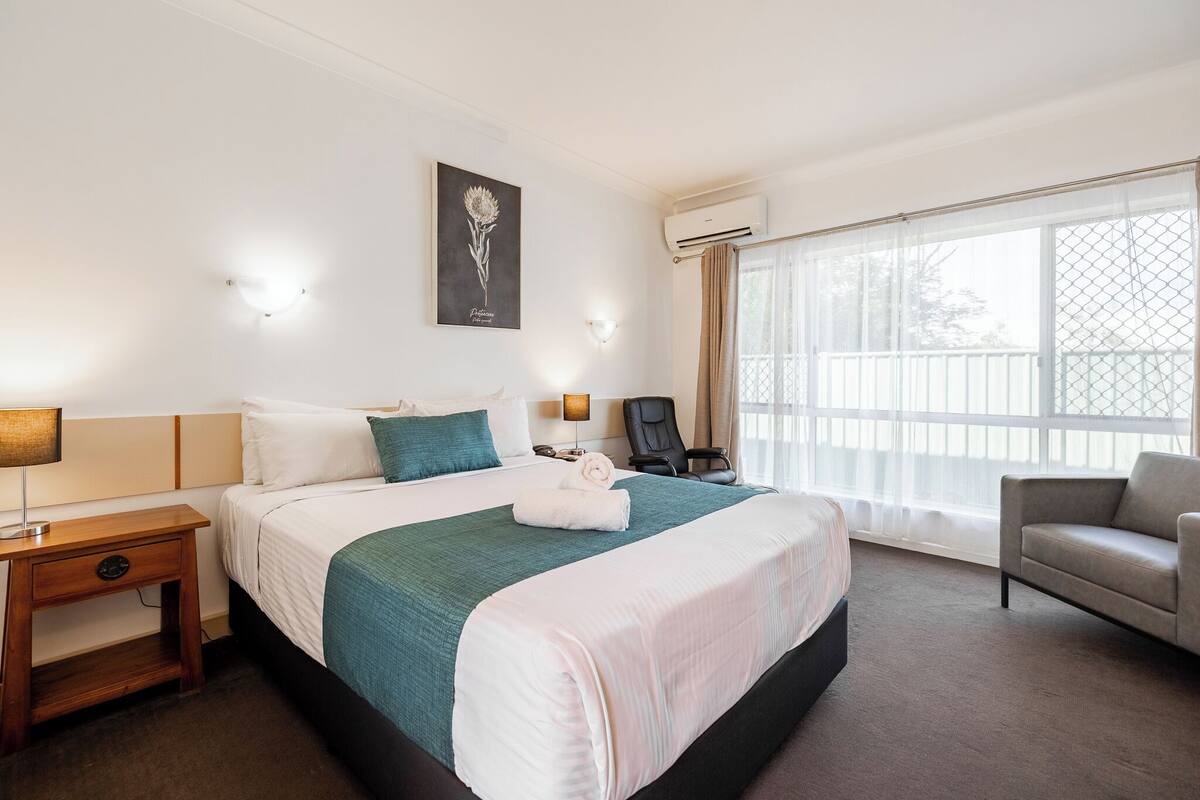 A hotel room with a large bed, a desk, a chair, and a window with a view.
