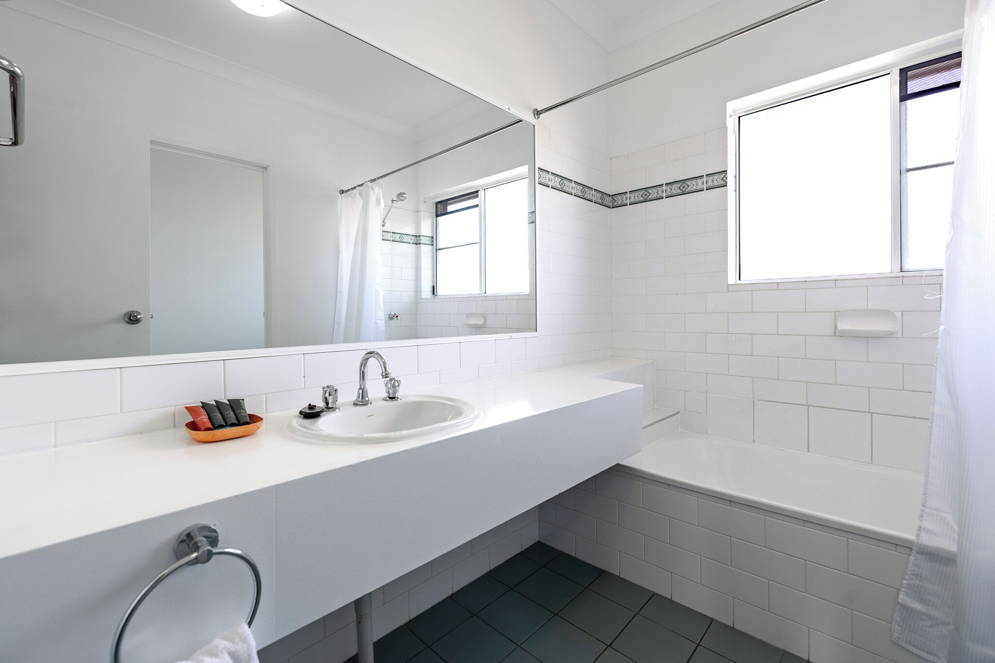 Ein modernes Badezimmer mit einem weißen Waschbecken, einer Badewanne und einem großen Spiegel.
