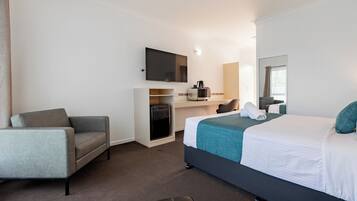 A hotel room with a bed, a sofa, a desk, a TV, and a microwave.