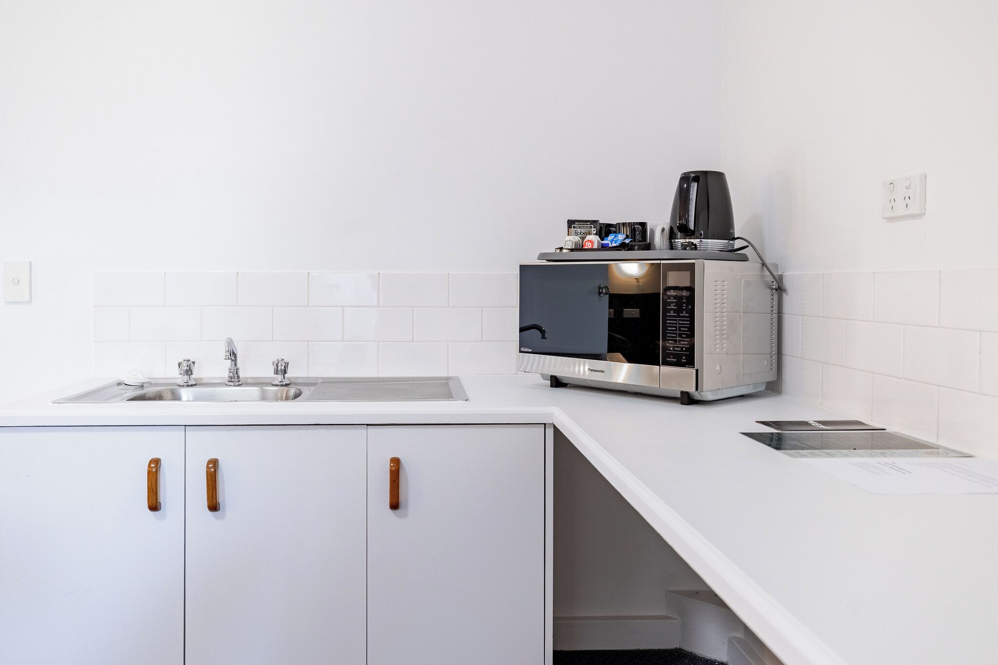 Una cuina moderna amb microones integrat, cafetera i un rentaplat.
