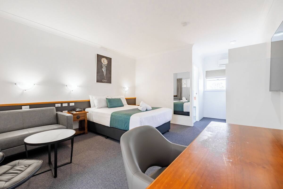A hotel room with a bed, a sofa, a small table, and a chair.