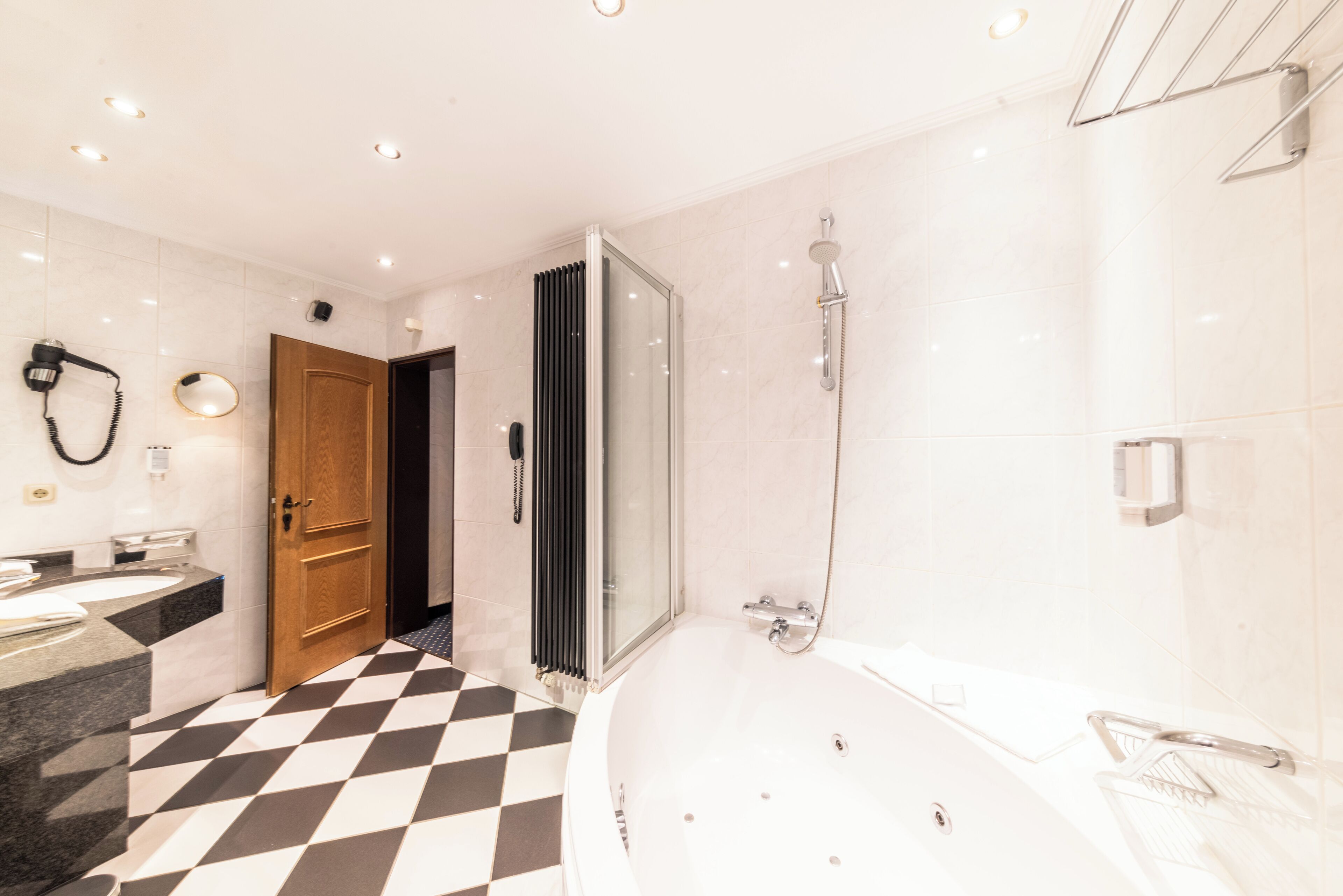 Un baño moderno con suelo a cuadros, una bañera, ducha y tocador con espejo.