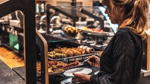 A buffet area with various food items and a person serving themselves.