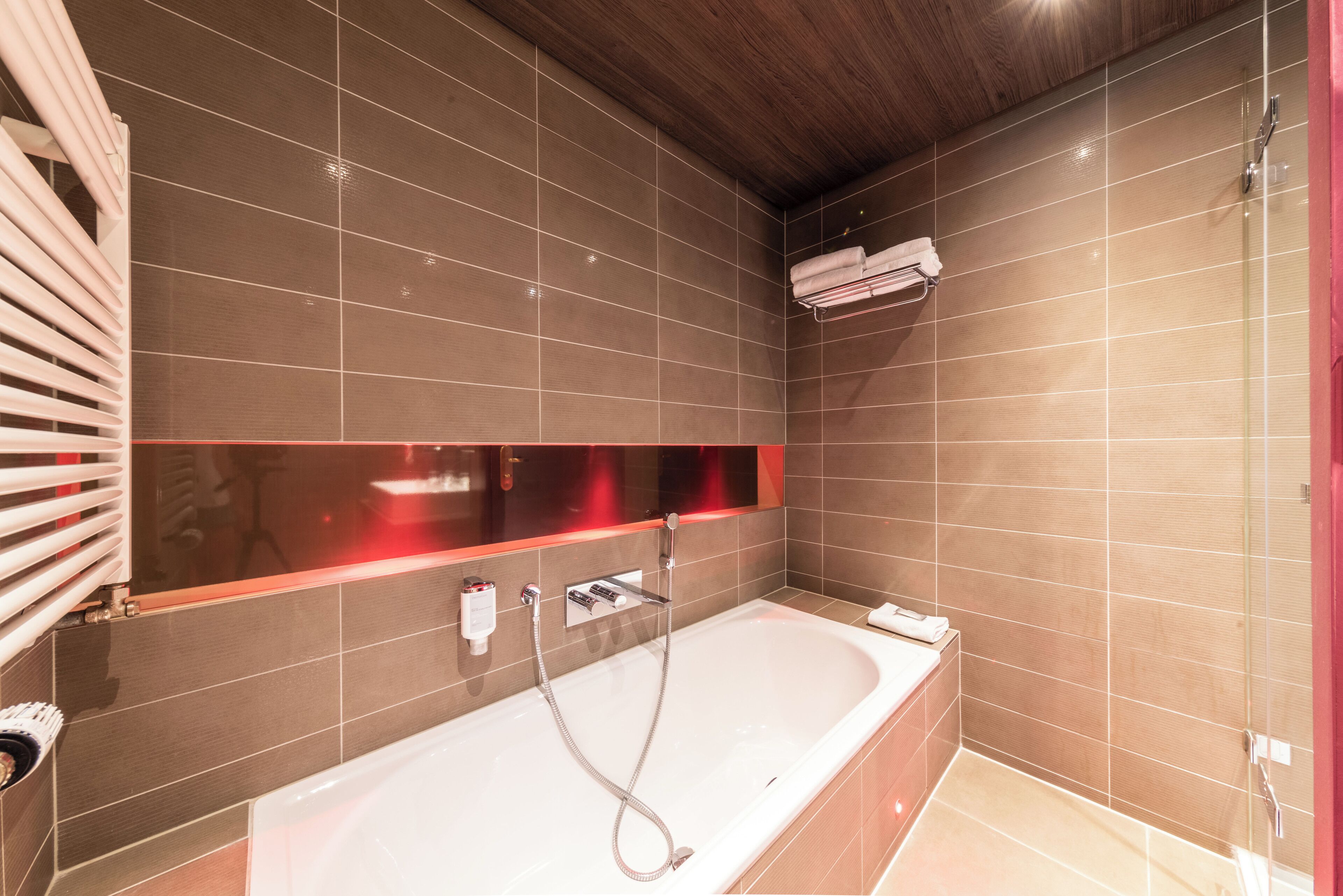 A modern bathroom with a large bathtub, a glass shower enclosure, and a towel rack.