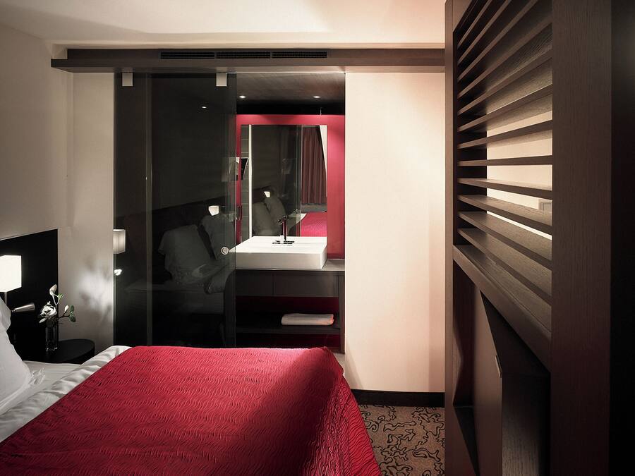 Una habitación de hotel con cama, escritorio, espejo y tocador.