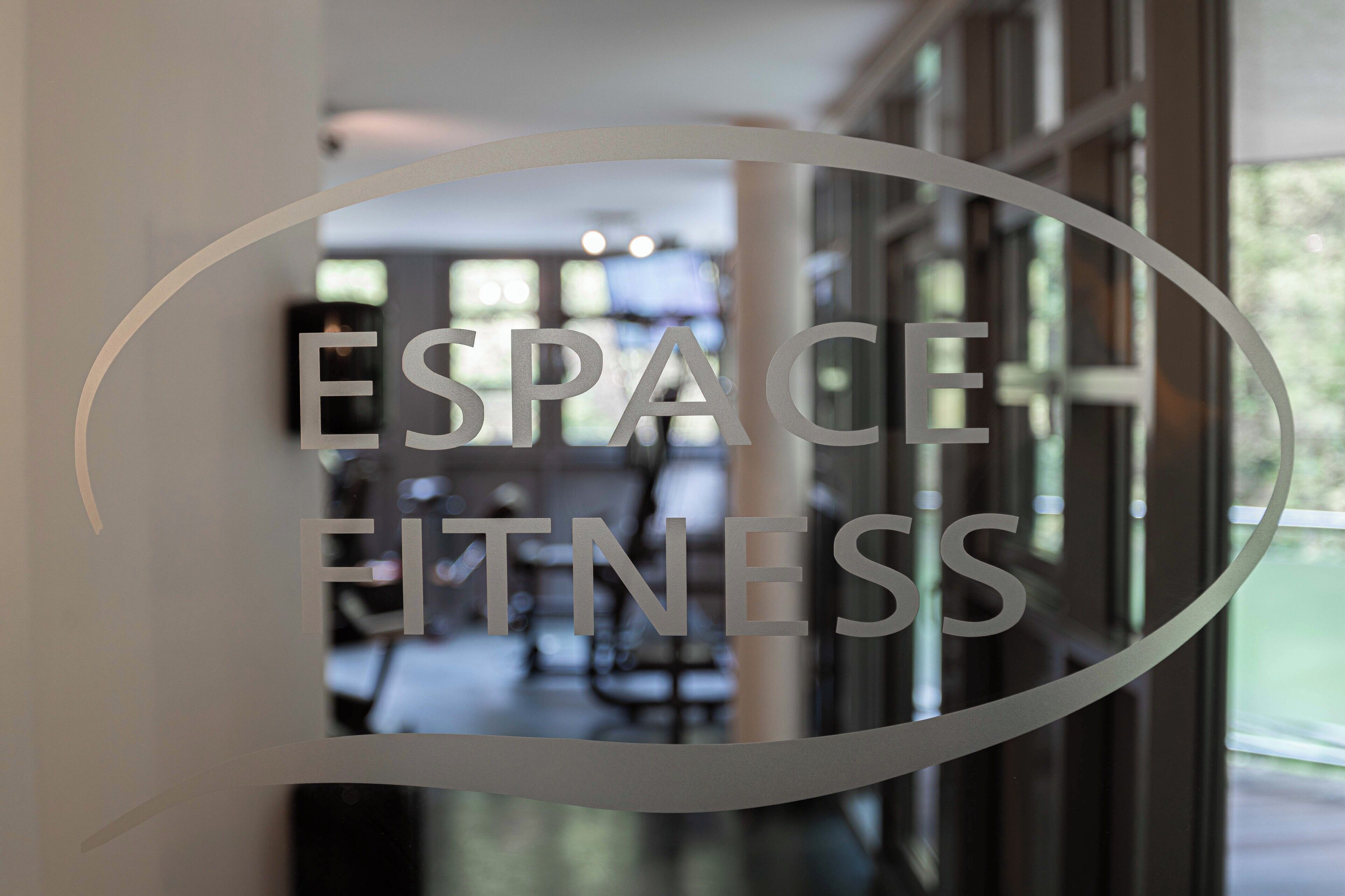 Una puerta de cristal con la inscripción grabada "ESPACE FITNESS".