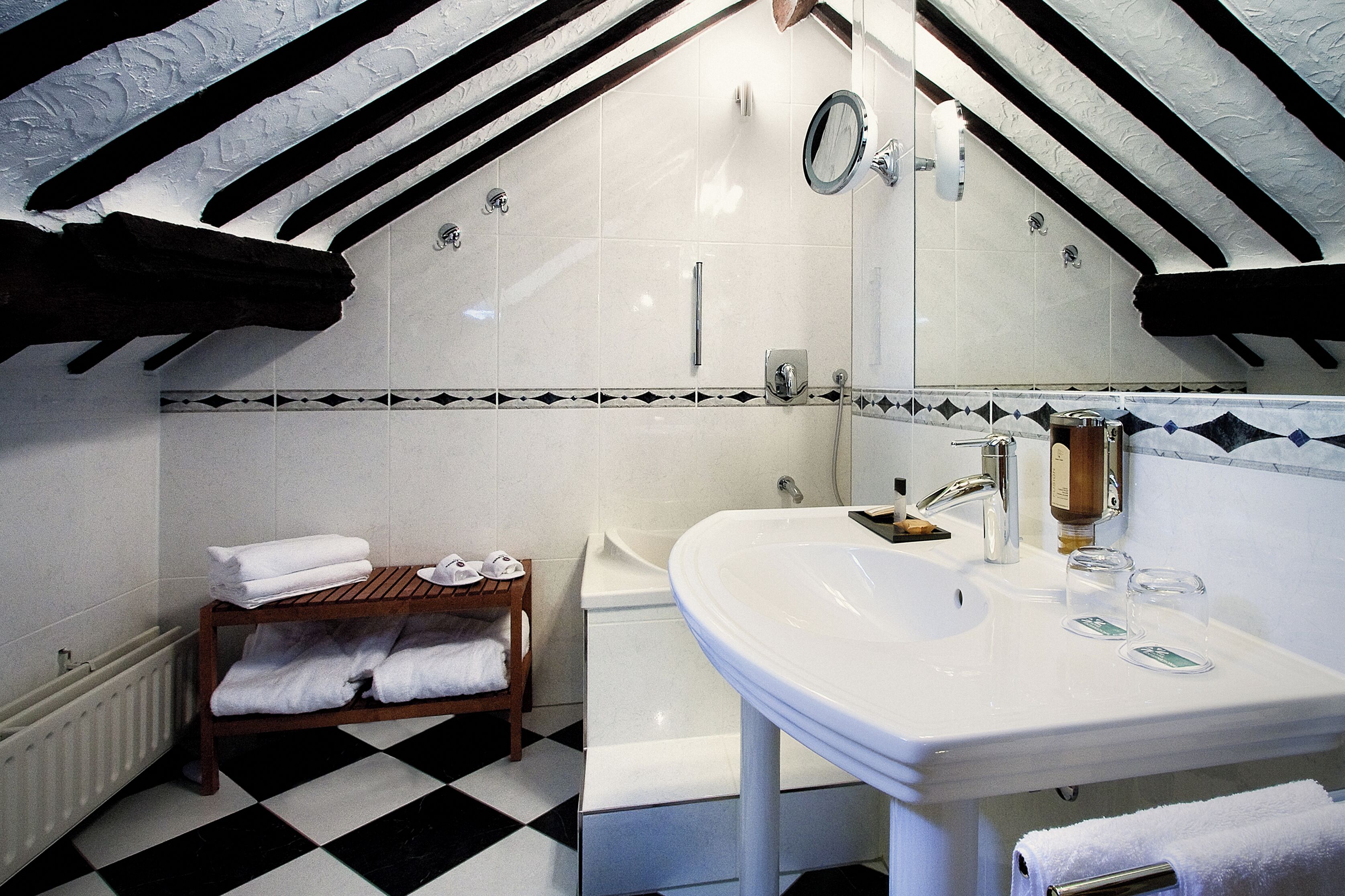 Ein Badezimmer mit einem weißen Waschbecken, einem Spiegel und einem Holzregal mit Handtüchern.