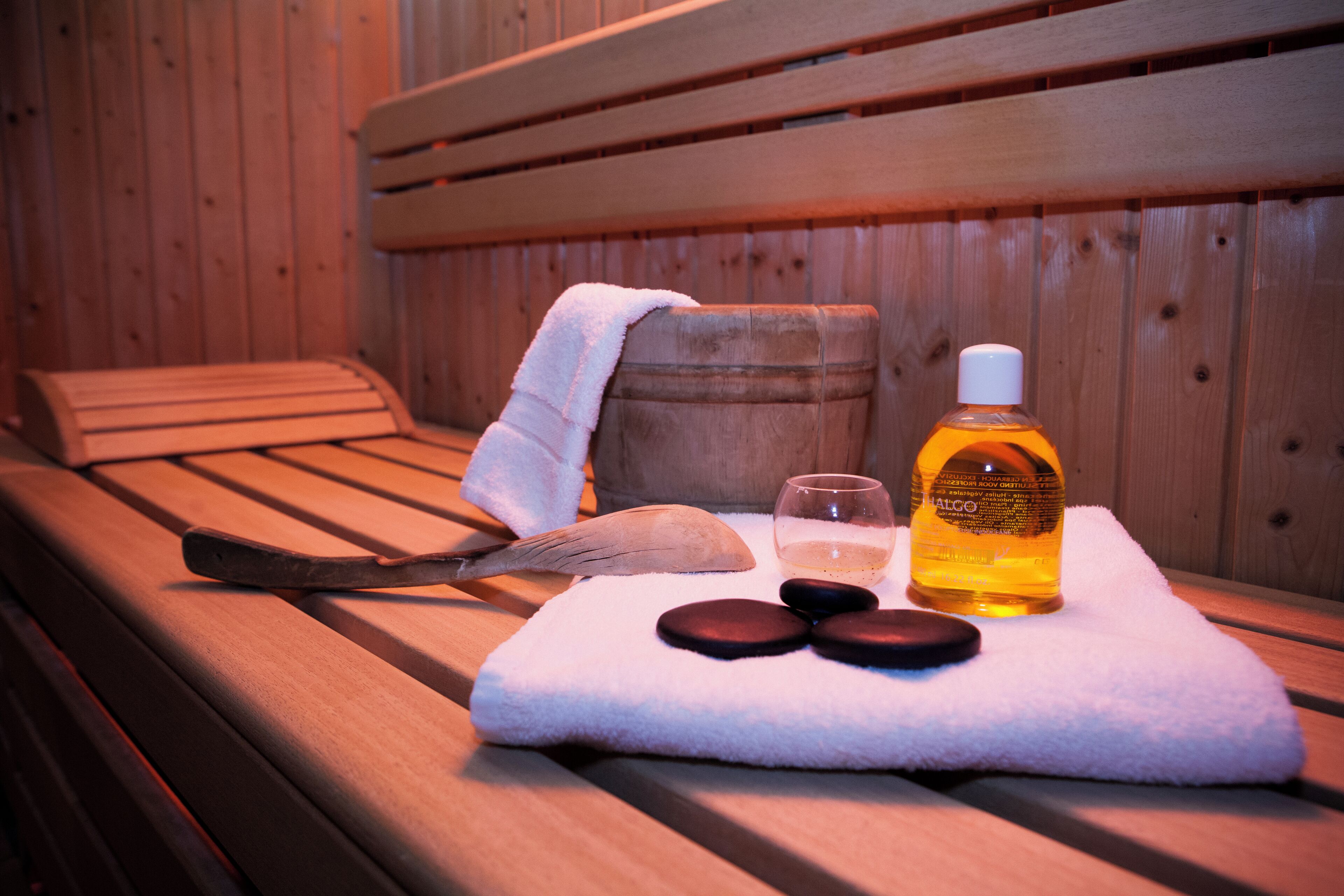 A wooden bench with a towel, a bottle of lotion, and two stones.