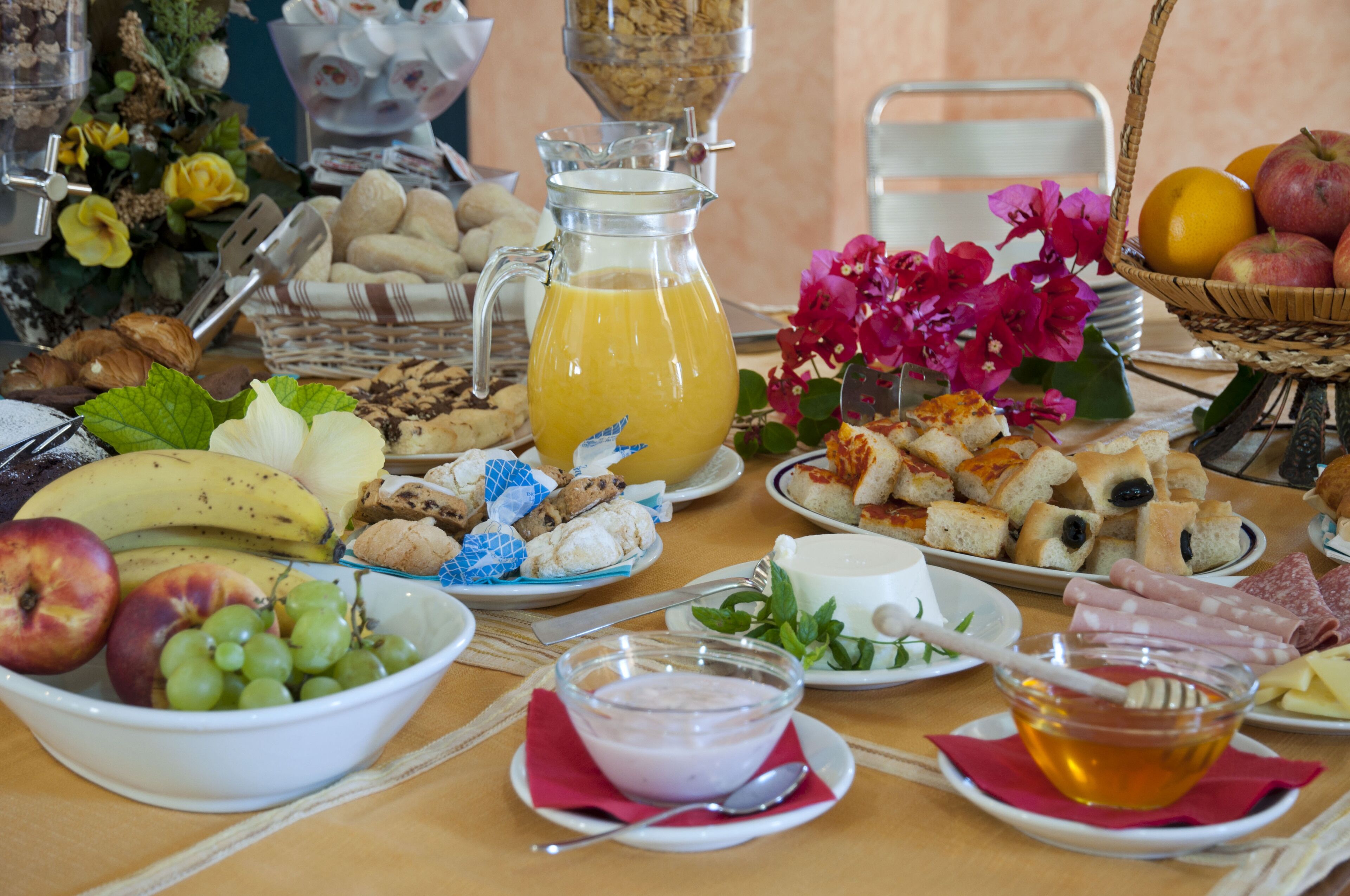 A breakfast buffet with various food items and a pitcher of orange juice.