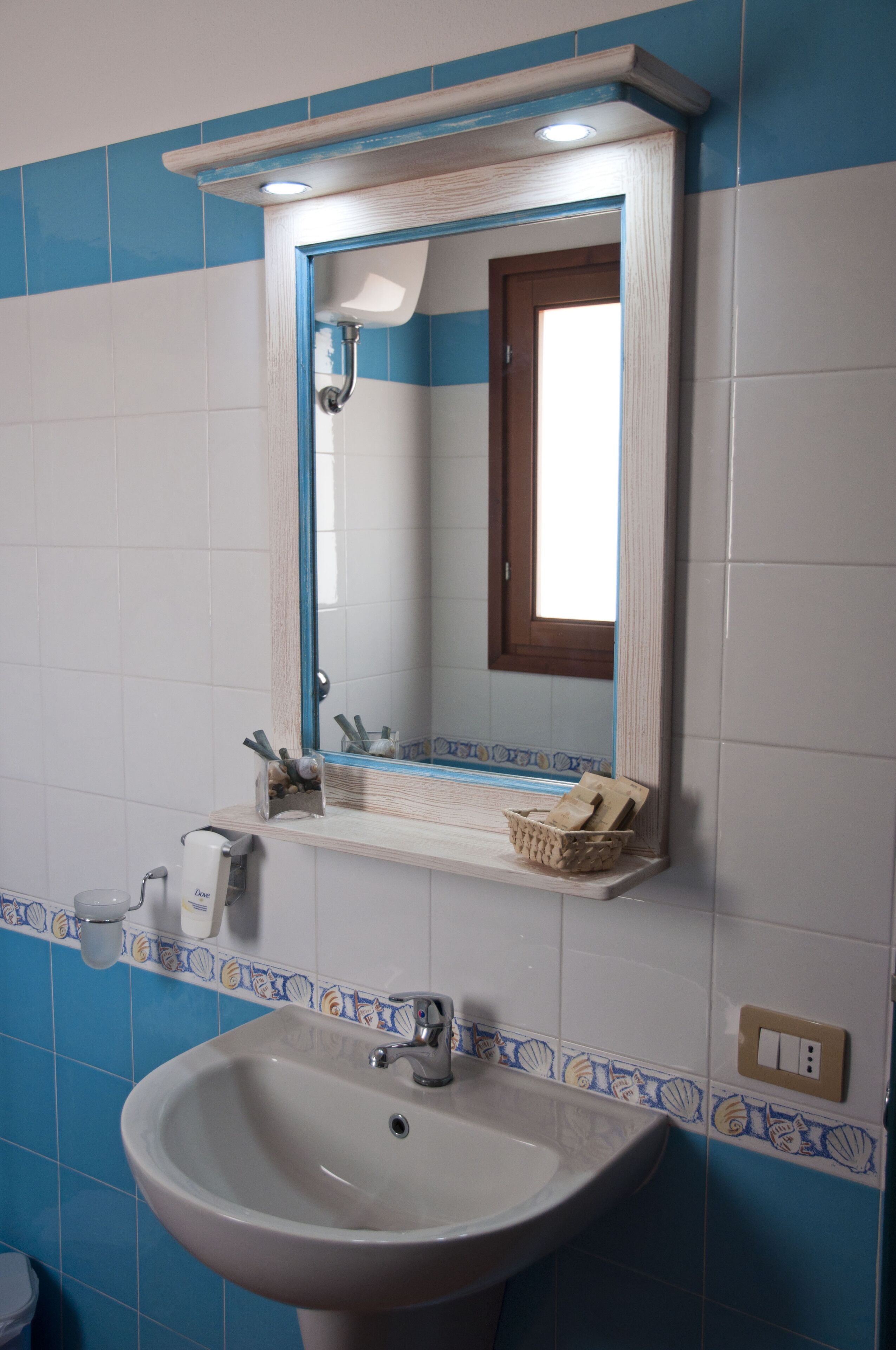 A bathroom with a white sink, a mirror, and a shelf with toiletries.