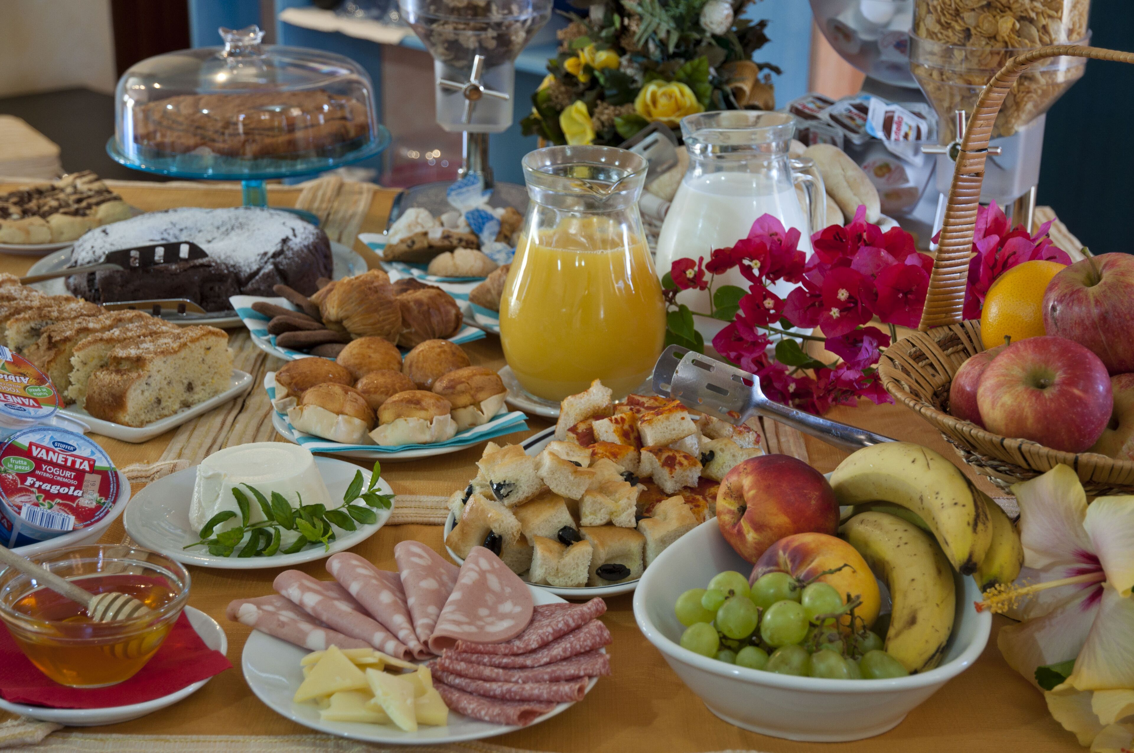 A breakfast buffet with various food items and a pitcher of orange juice.