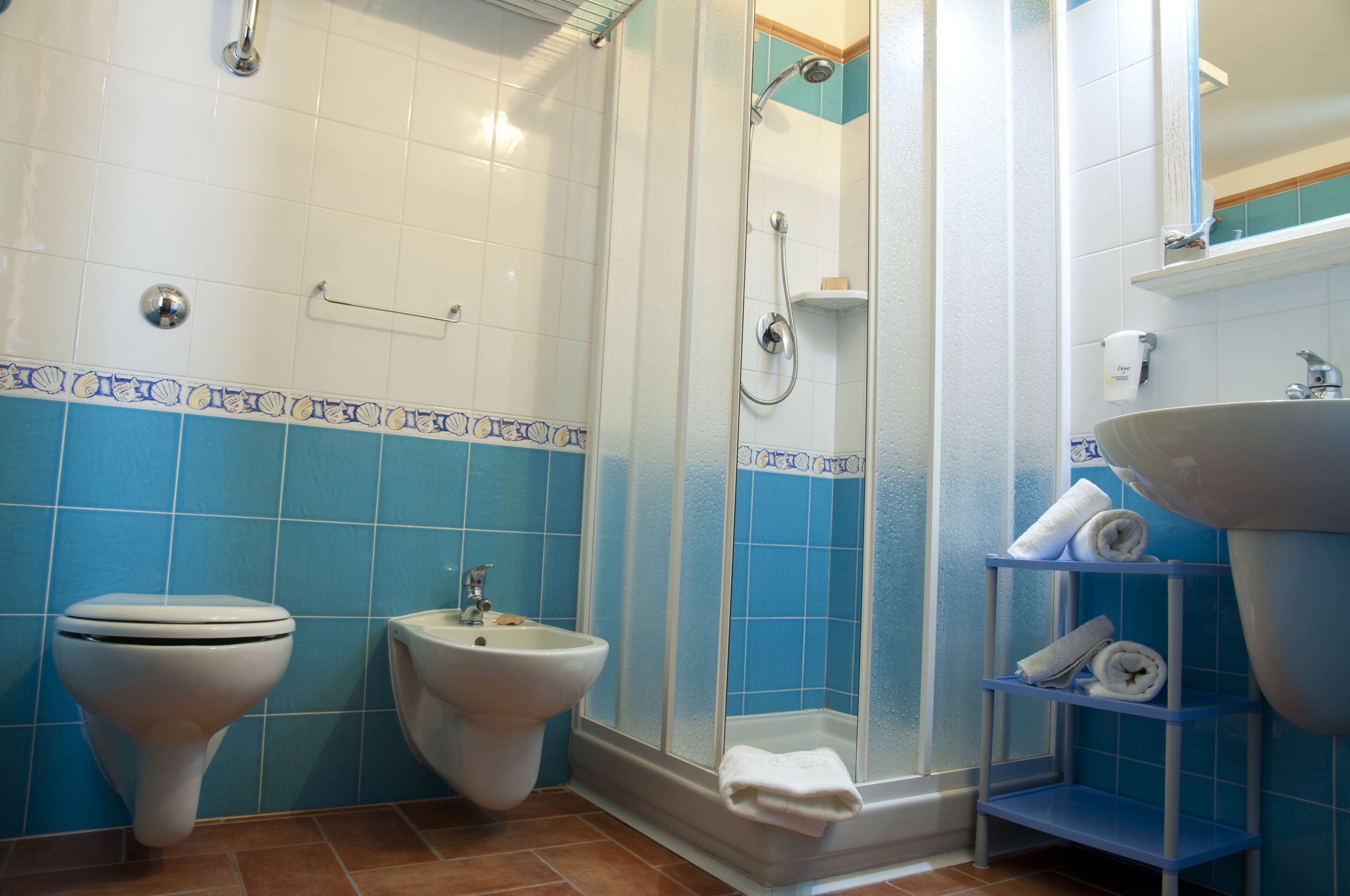 Un baño con inodoro, bidé, ducha, lavamanos y toallero.