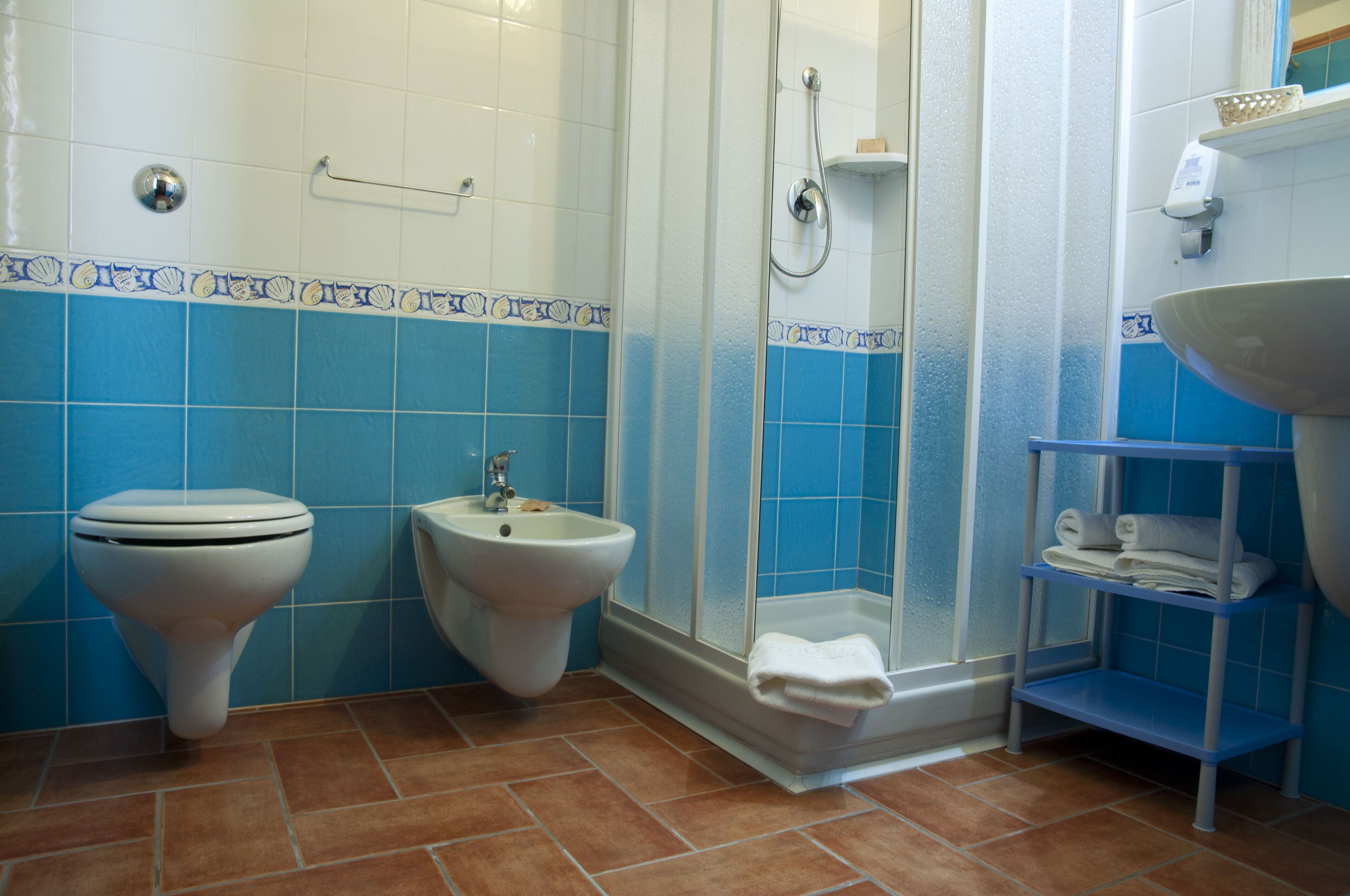 Une salle de bain comprenant des toilettes, un bidet, une douche et un lavabo.