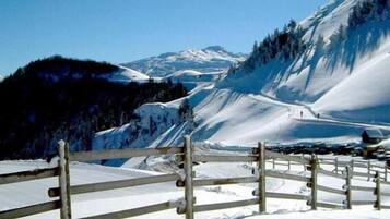 A snow-covered mountain landscape with a wooden fence in the foreground.