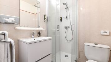 A bathroom with a glass-enclosed shower, a white sink, and a toilet.
