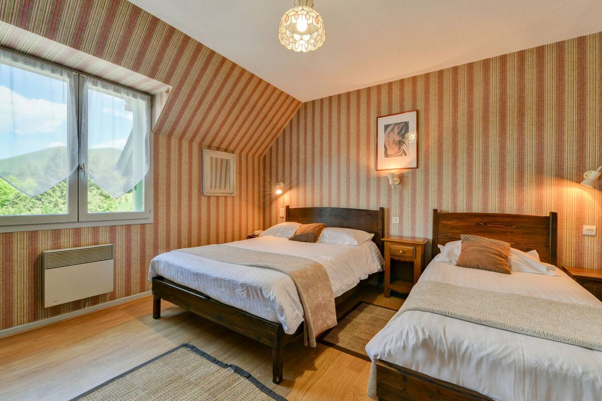A bedroom with two beds, a window with curtains, a radiator, and a wall-mounted picture.